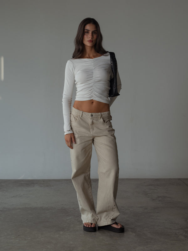 Modelo usando jean crema con top manga larga recogido frontal crudo.