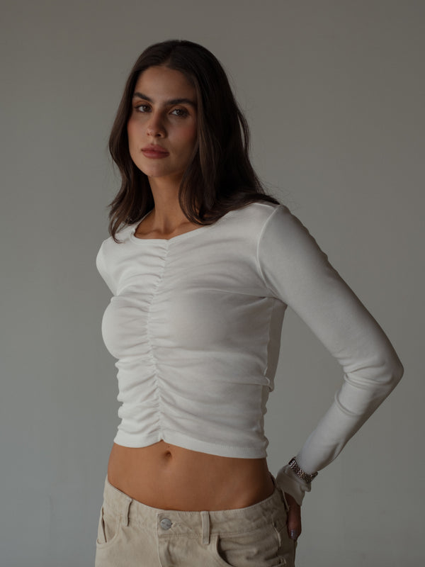 Modelo usando top recogido crudo manga larga con jean crema.