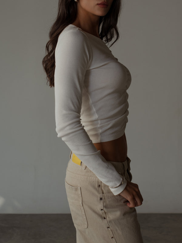 Vista lateral modelo con top manga larga crudo con jean crema.