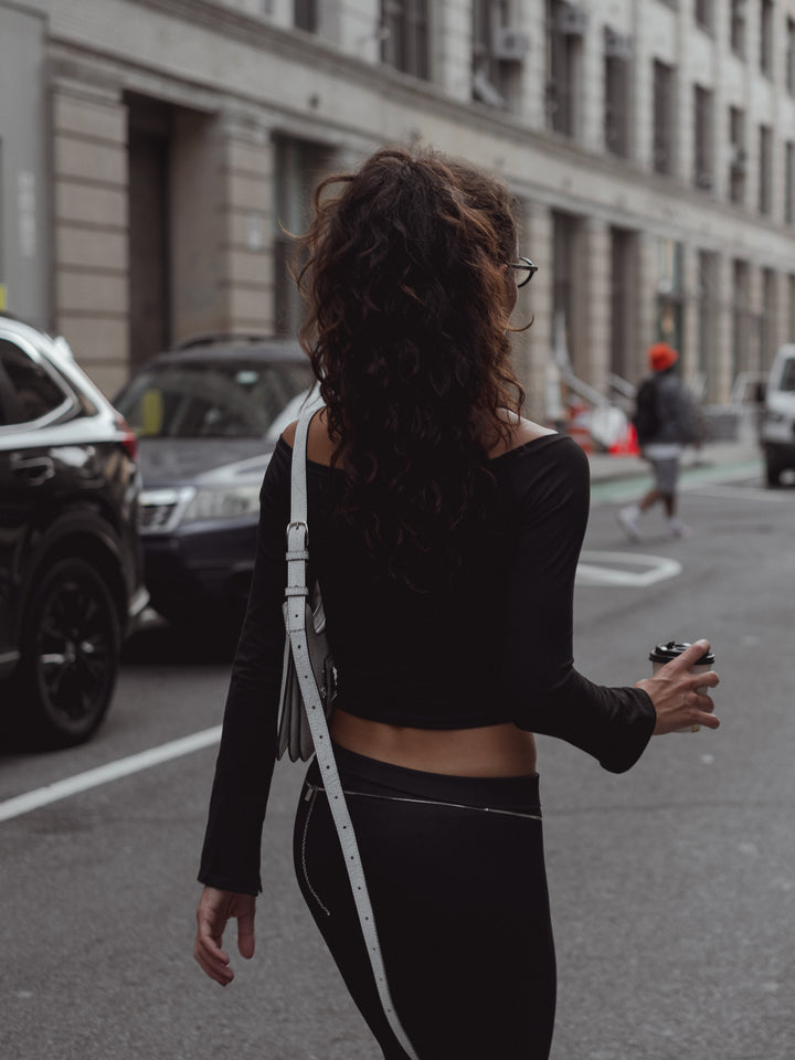 Vista de espalda modelo caminando con look casual negro. 