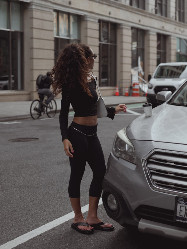 Modelo en la calle vistiendo Capri negro y top negro manga larga con sandalias.