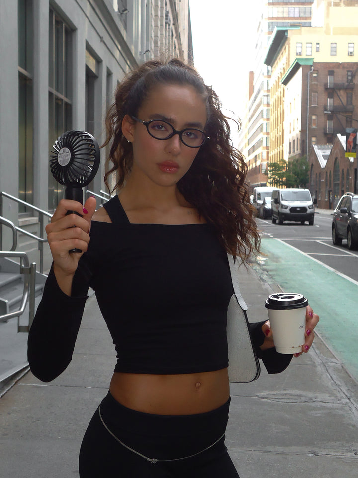 Modelo en la calle usando accesorios con top bandeja manga larga negro.