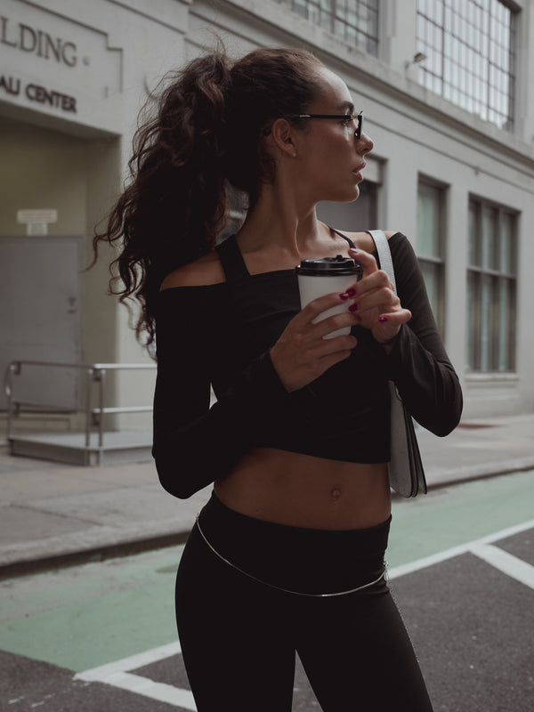 Mujer en la calle con vaso de calle y look casual negro. 