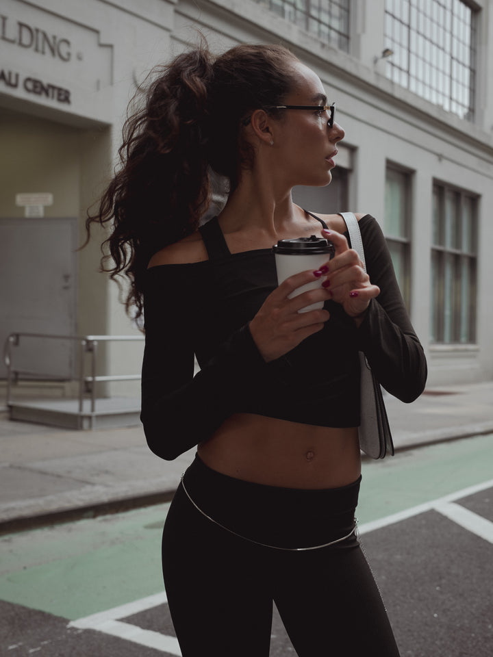 Mujer en la calle con vaso de calle y look casual negro. 