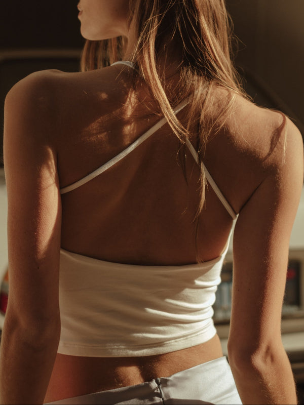 Vista posterior modelo usando crop top de tiras de espalda cruzada crudo.