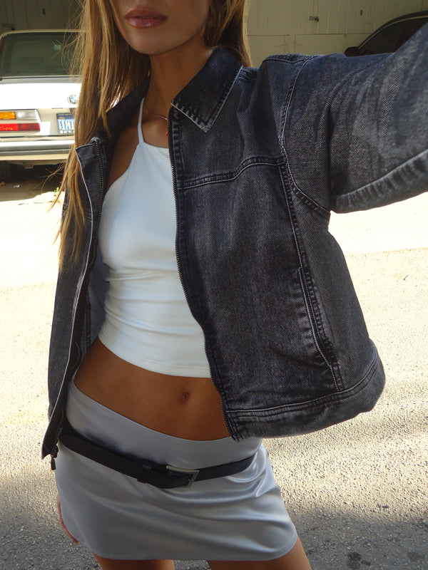 Modelo con crop top crudo halter, chaqueta y mini falda satinada plata.