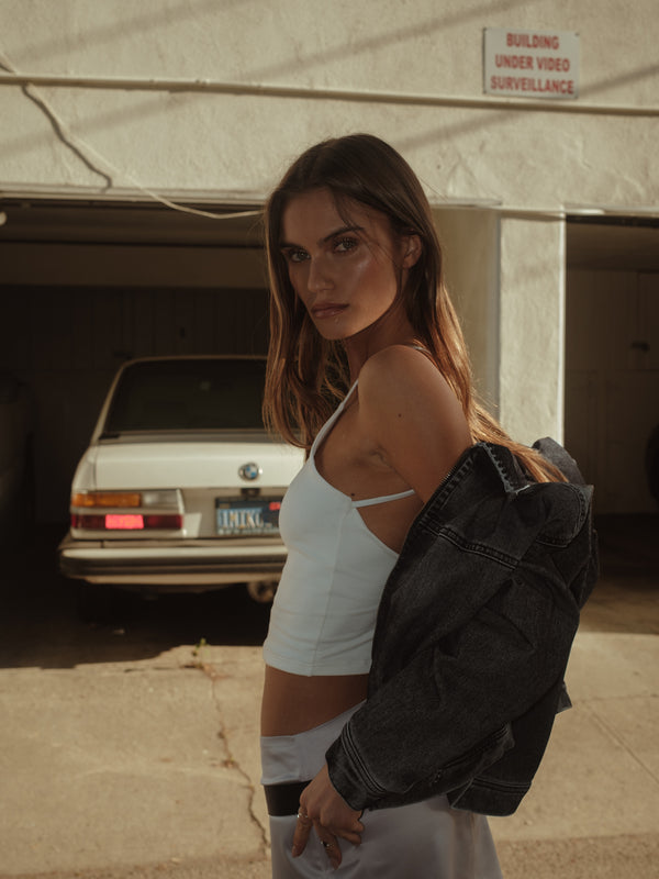 Vista lateral modelo con crop top tipo halter crudo, mini falda y chaaqueta.