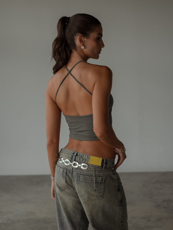 Vista posterior de modelo usando crop top gris espalda cruzada.