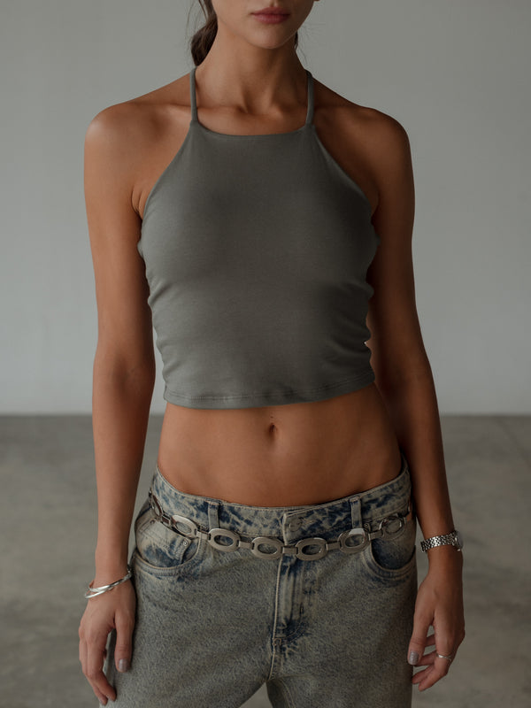 Vista frontal modelo usando crop top gris halter ajustado con jean.