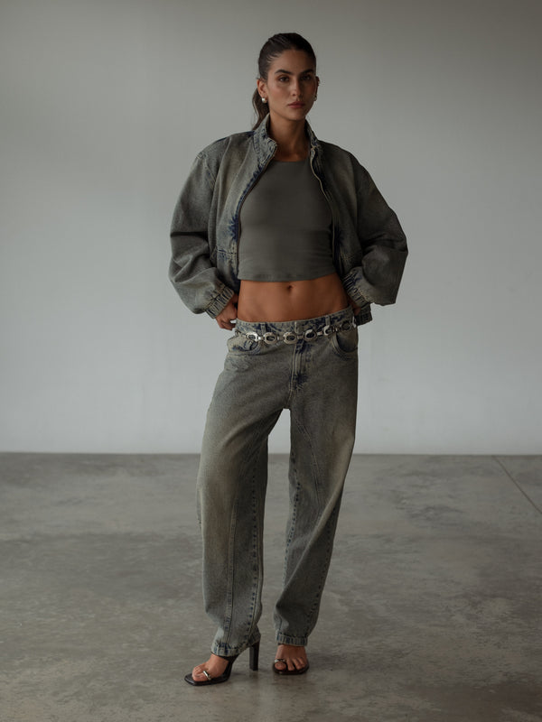 Modelo con crop top gris halter con chaqueta y jean azul vintage.