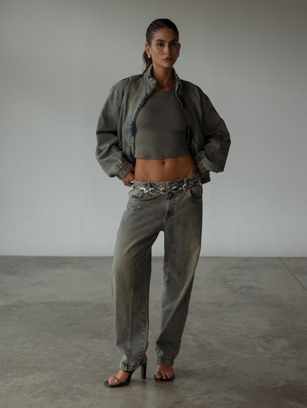 Modelo con crop top gris halter con chaqueta y jean azul vintage.