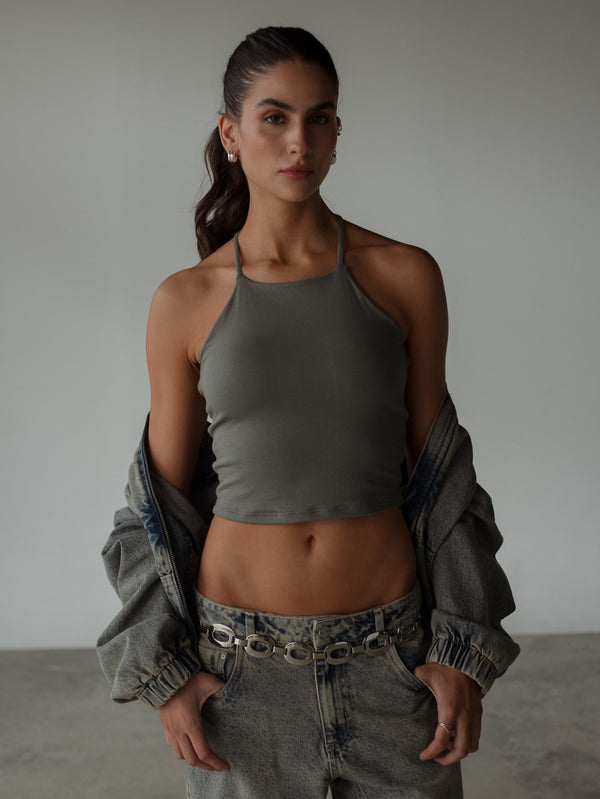 Modelo con crop top gris halter con chaqueta y jean.
