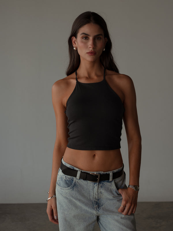 Vista frontal modelo con crop top halter negro de tiras con jean.