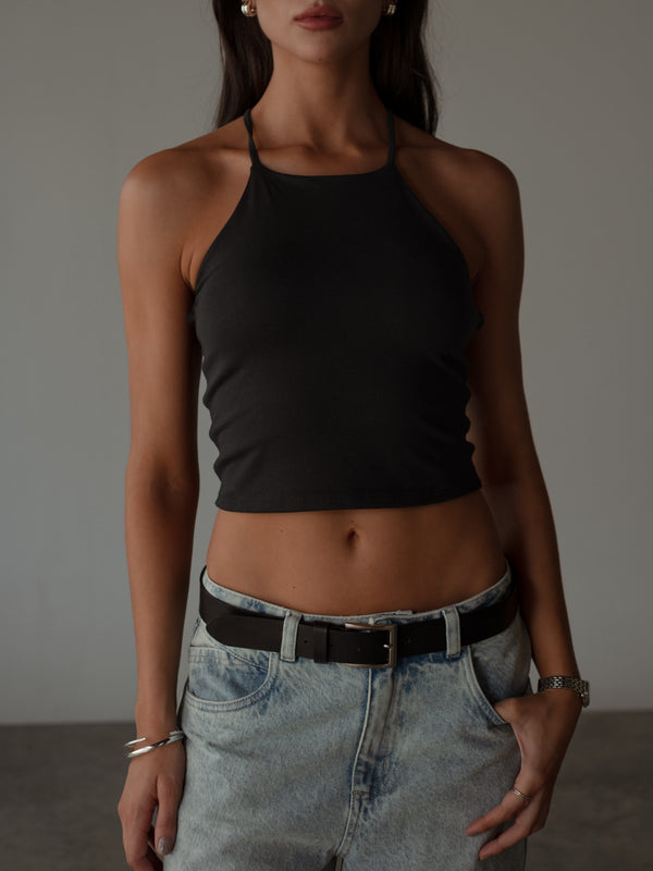 Modelo con top halter negro básico con jean y cinturón negro.
