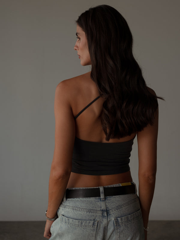 Vista posterior de modelo usando crop top negro espalda cruzada.