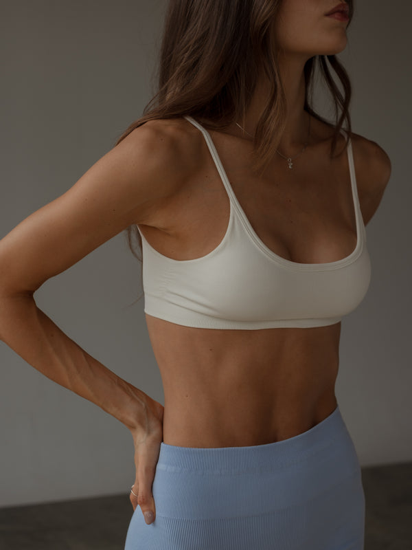 Modelo con top de tiras crudo sin costuras y short deportivo azul.