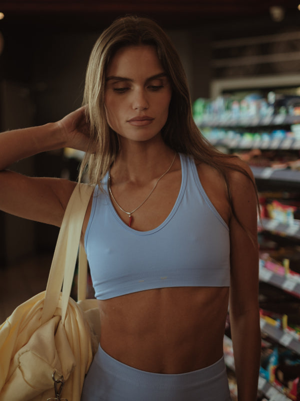 Modelo usando top deportivo azul claro, ajustado al cuerpo.