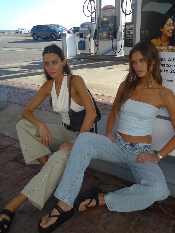 Dos modelos sentadas en la calle usando ropa casual para mujer.