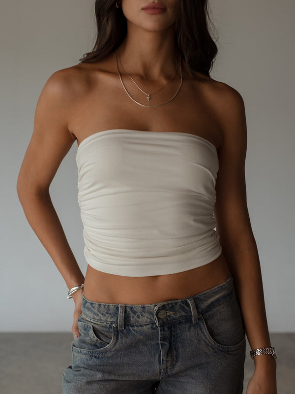 Modelo usando crop top crudo strapless con drapeado lateral.