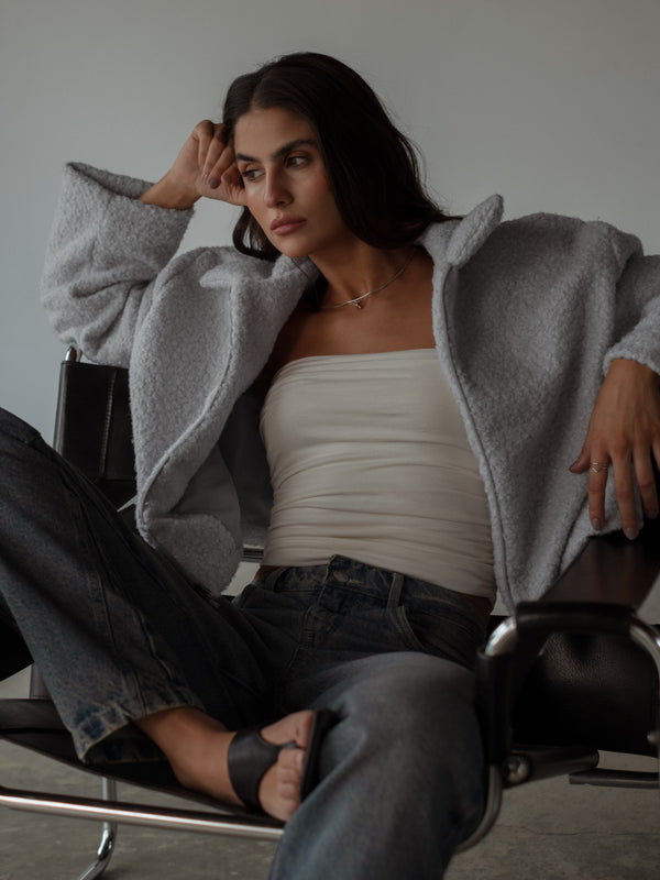 Modelo usando chaqueta con crop top crudo strapless drapeado y jean.