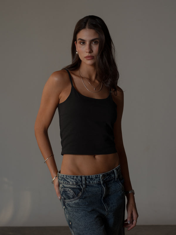 Modelo usando crop top básico de tiras con jean azul.
