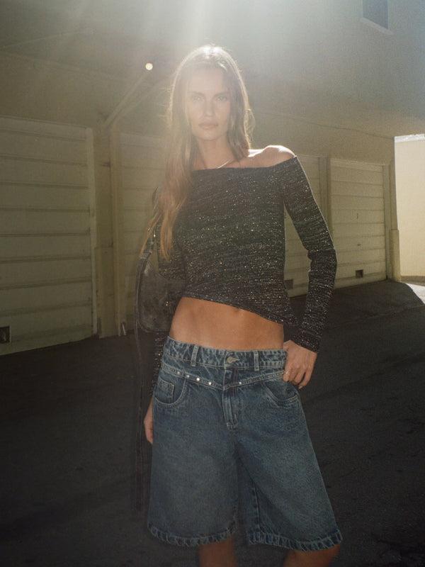 Modelo usando top manga larga tejido negro con brillos  short.