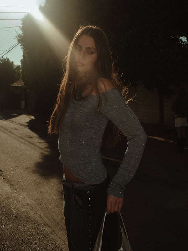 Modelo usando top manga larga tejido gris con brillo y jean gris.