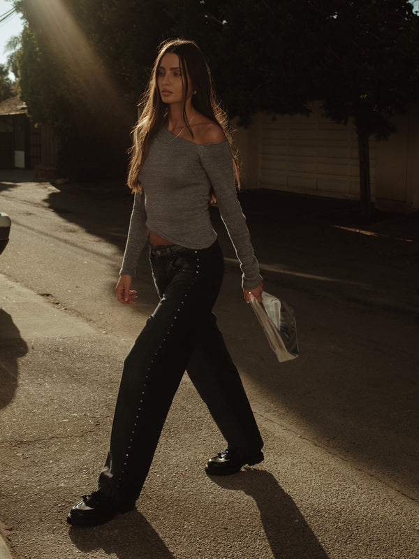 Modelo caminando usando jean gris con top tejido manga larga gris.