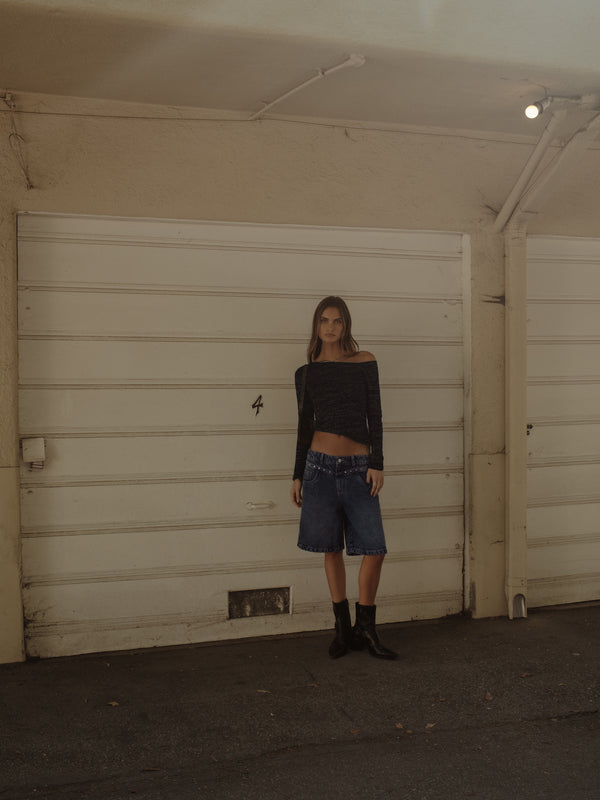 Modelo con short y top diagonal negro brillante con botas.