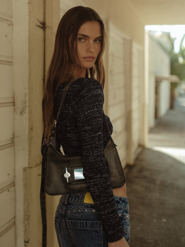 Vista posterior modelo con top tejido negro con brillo ruedo diagonal.