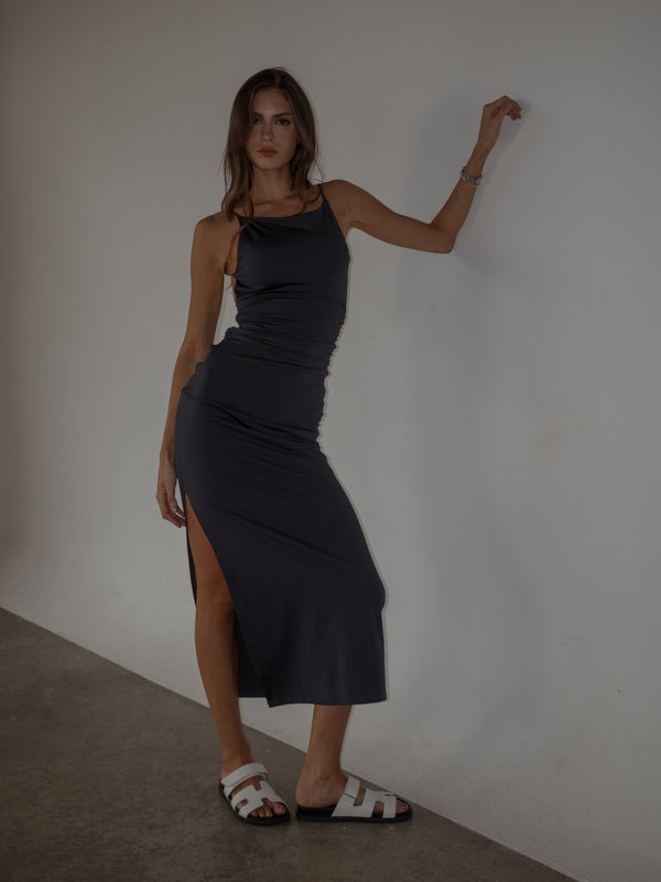 Modelo usando vestido púrpura con laterales drapeados ajustado.