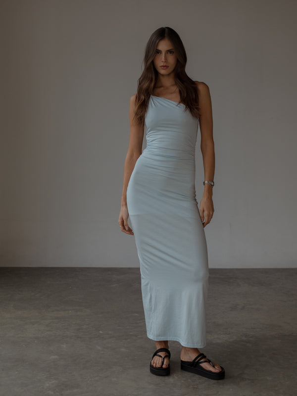 Modelo usando vestido largo azul claro con drapeado lateral.