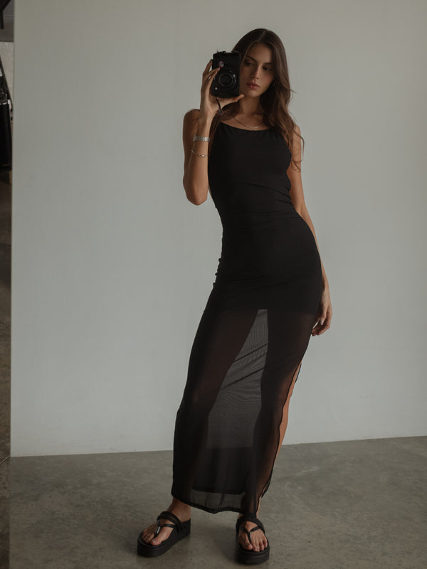 Modelo tomándose una foto en espejo usando vestido largo negro.