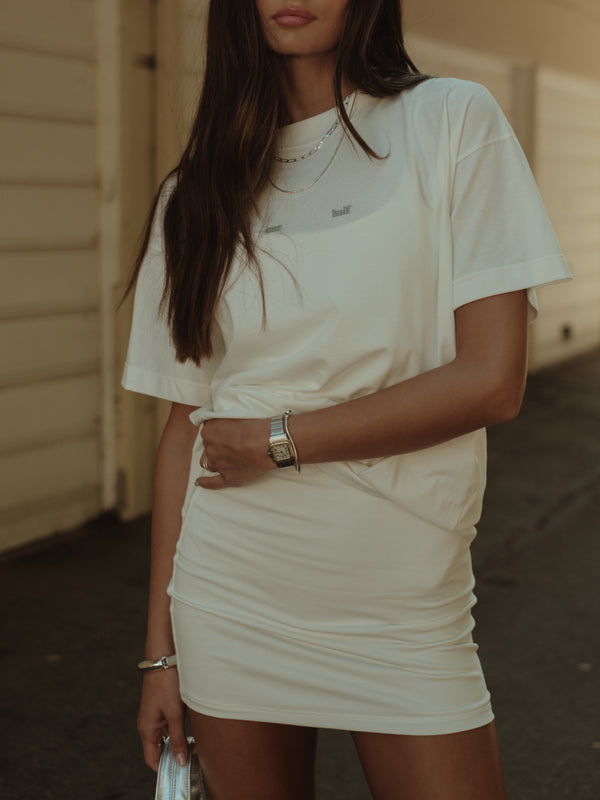 Modelo usando camiseta crudo sobre mini vestido crudo. 