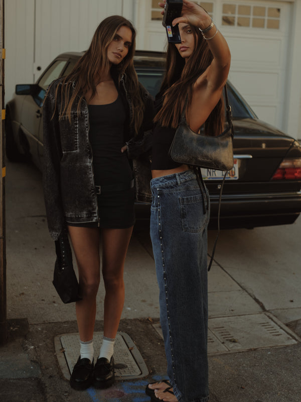 Dos modelos tomándose una foto en estacionamiento. 