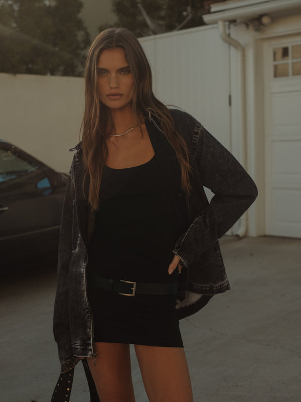 Vista frontal modelo con mini vestido negro y chaqueta oversized.
