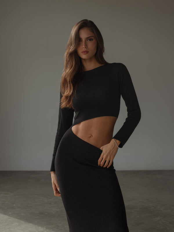 Modelo usando vestido negro con abertura asimétrica en abdomen.