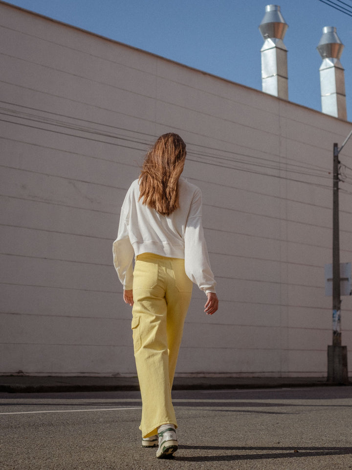 Vista posterior de jean cargo amarillo y buzo oversized blanco